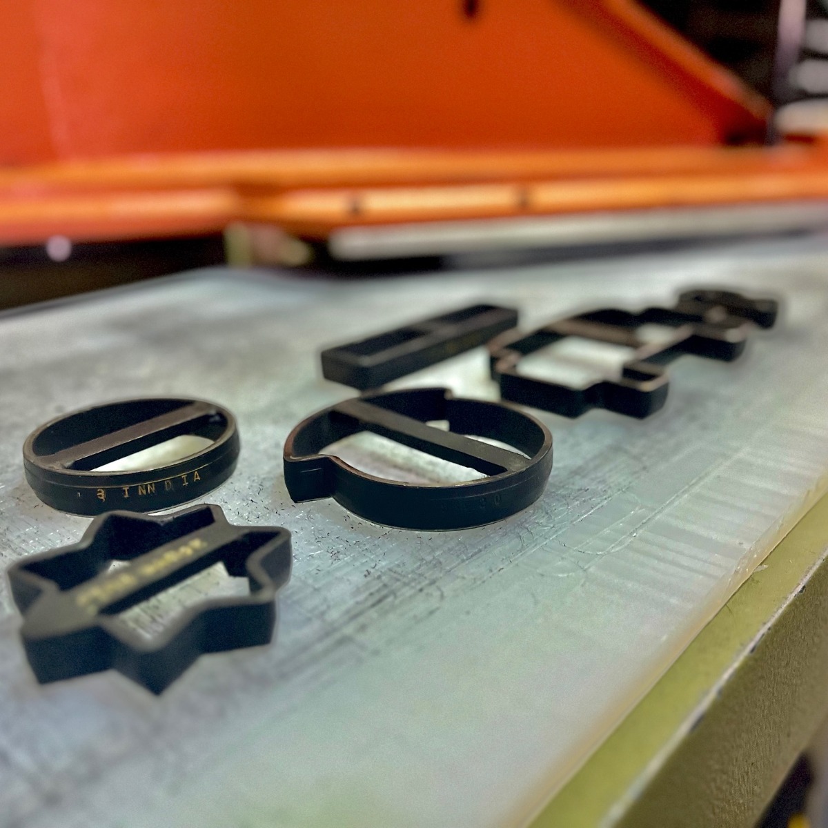 Custom die cutting machine cutting metal letters for industrial manufacturing process