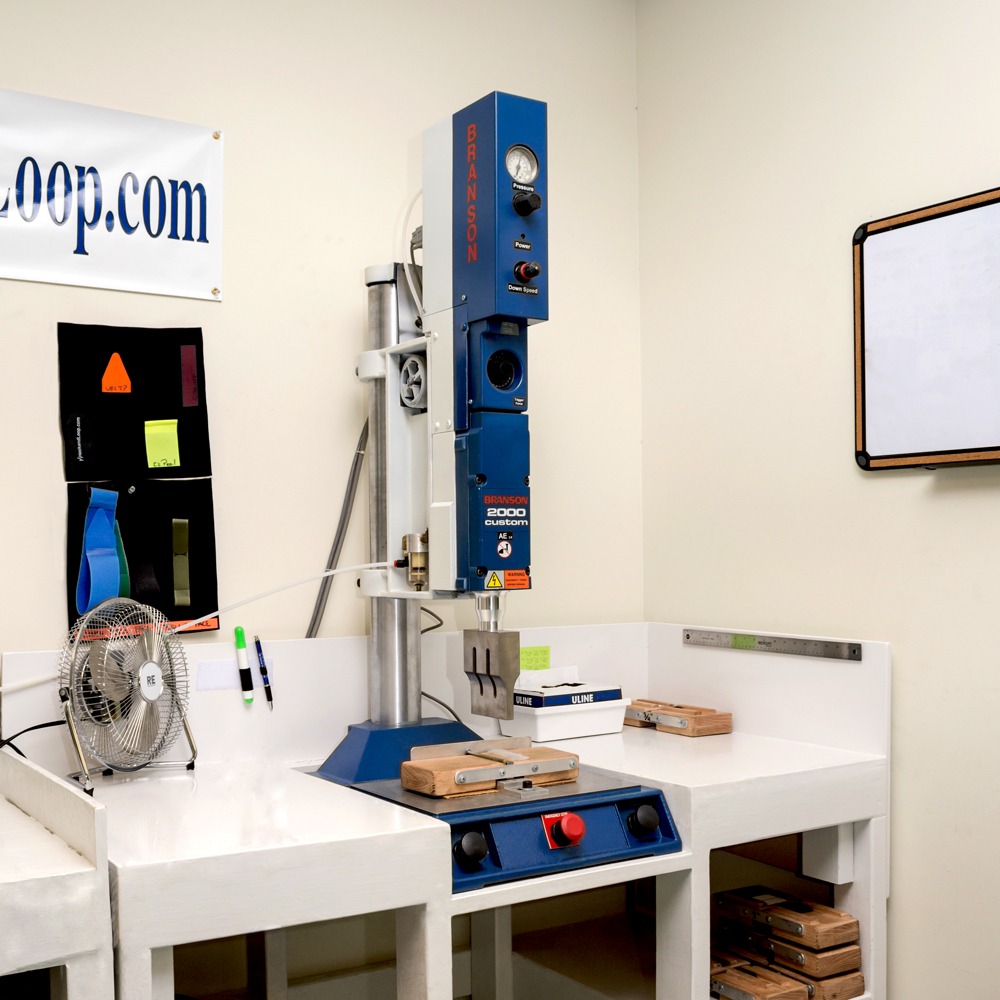 An industrial benchtop ultrasonic welding machine (Branson 2000 custom) setup in a workshop or manufacturing area.