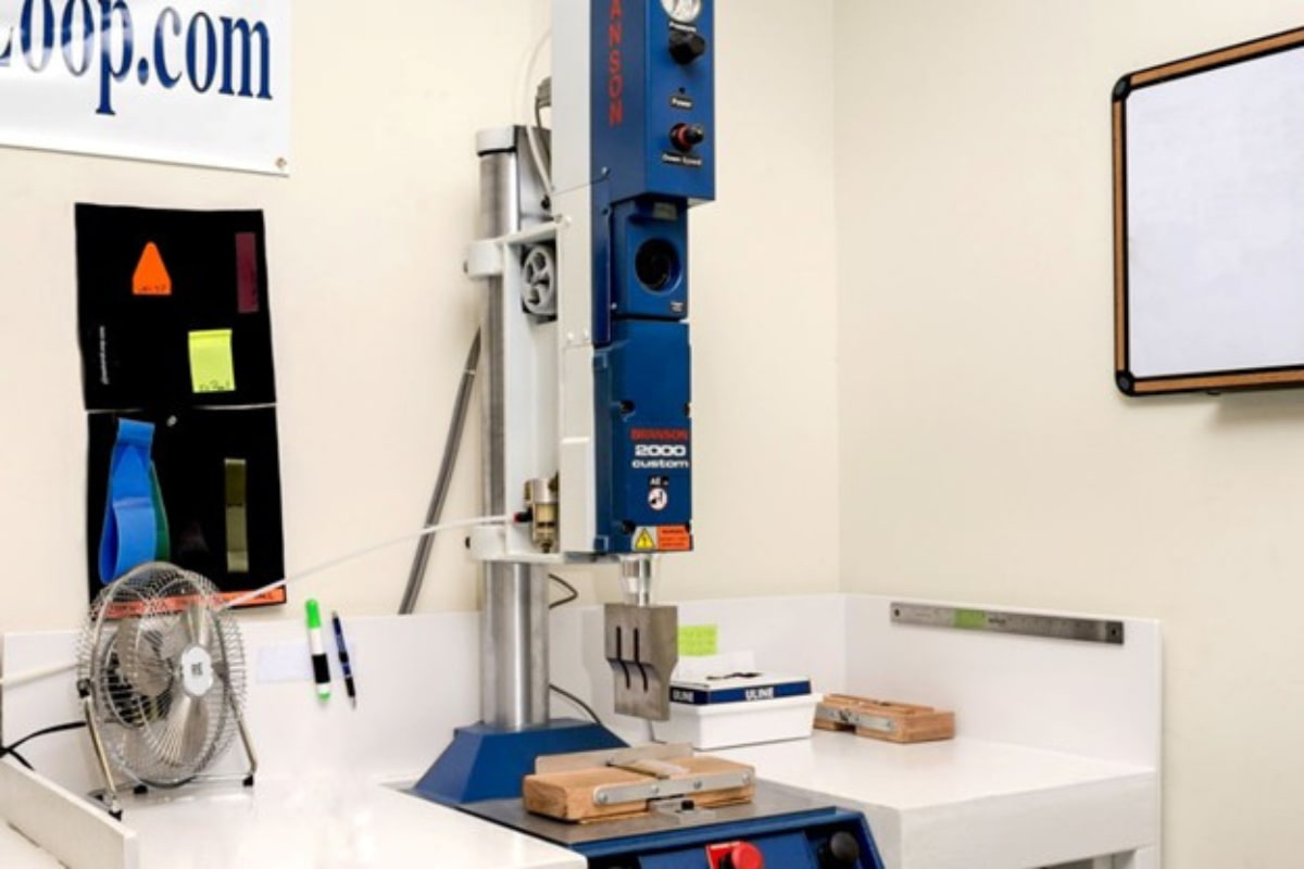 An industrial benchtop ultrasonic welding machine (Branson 2000 custom) setup in a workshop or manufacturing area.